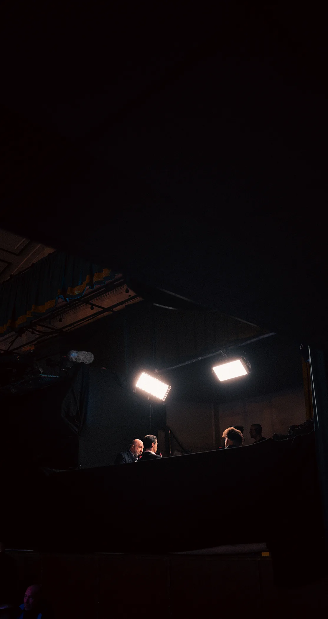 Crew at monitors under two panel lights in a darkened studio