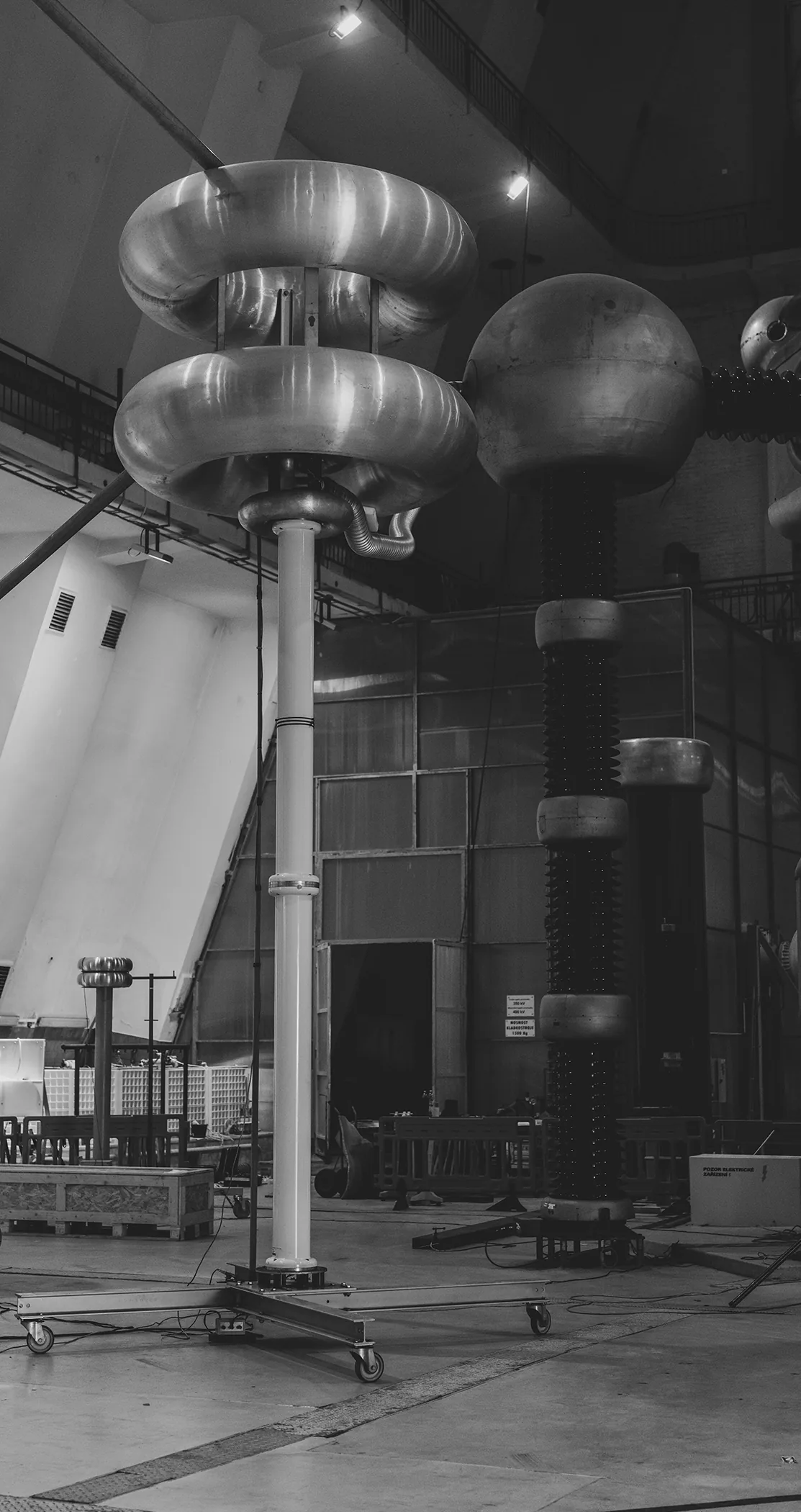 Towering high-voltage generators in a vast hall, in black and white, Prague